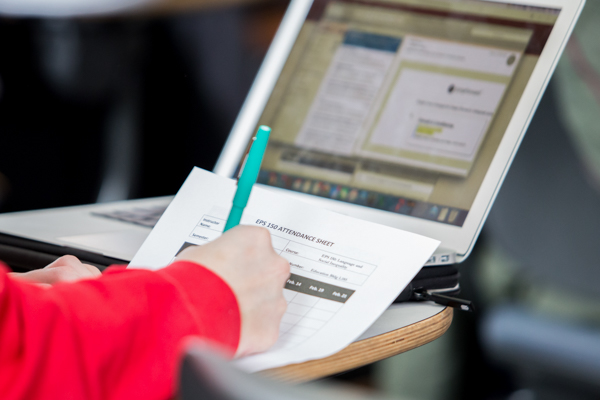 student writing and using laptop in Undergraduate Course