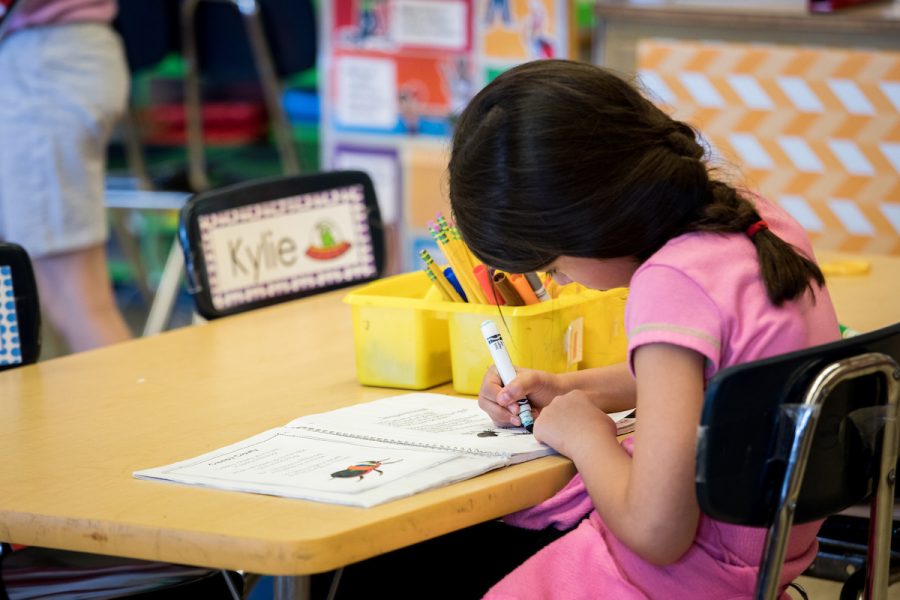 child sitting at a desk drawing